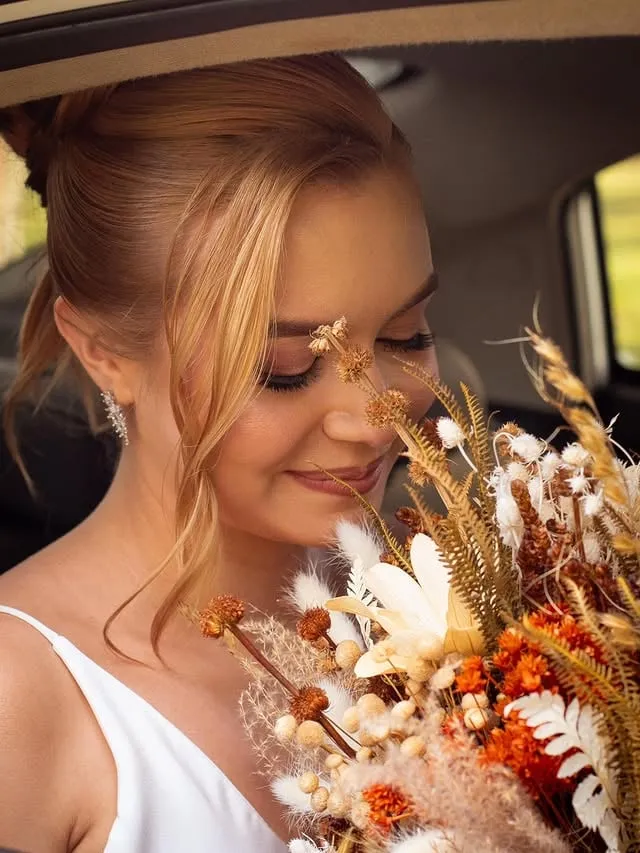 Noiva segurando buquê de flores secas dentro do carro